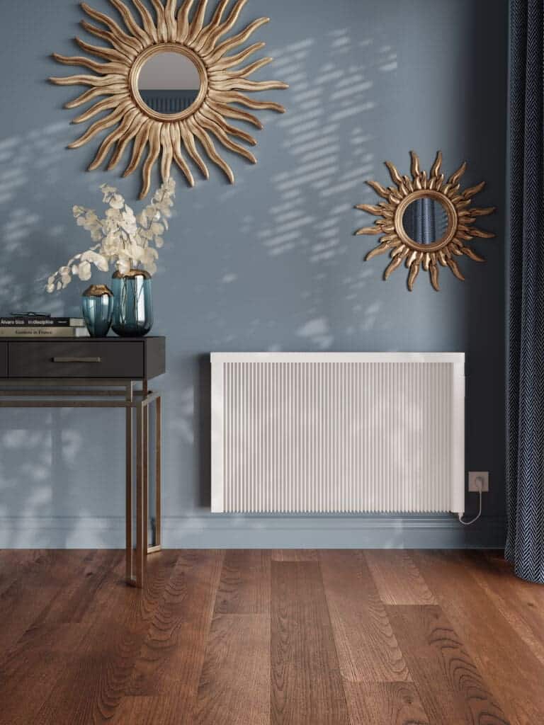 Warm white modern radiator on blue wall with decorative mirrors and wooden flooring.