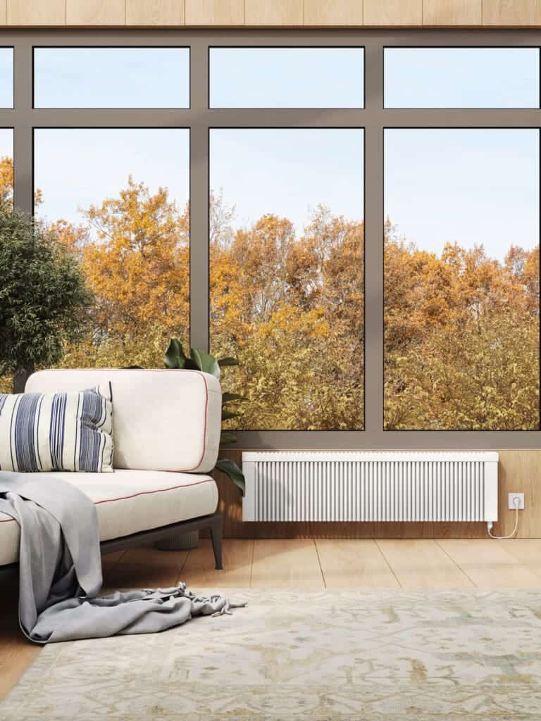Modern living room with large window showing autumn trees, featuring a sleek white radiator.